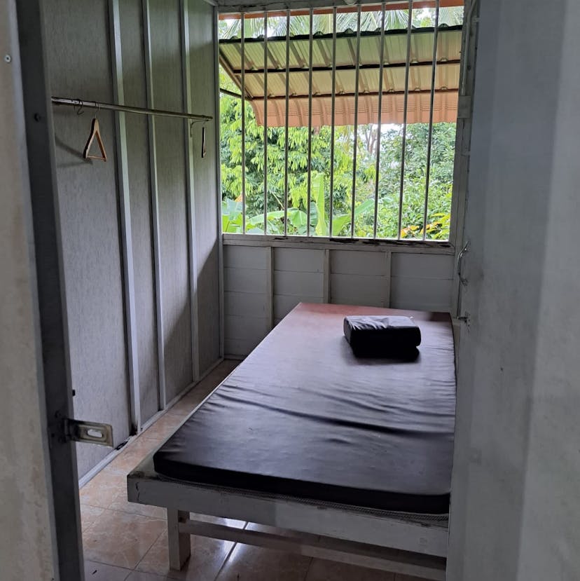 A bed in a simple room with bars on the window