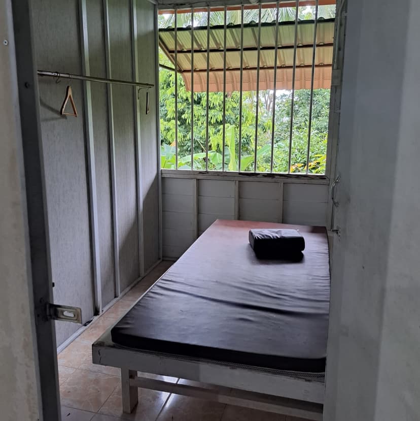 A bed in a simple room with bars on the window