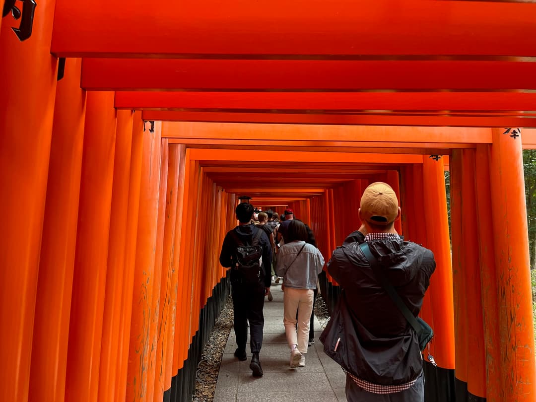 Jonathan taking a picture under red gates at a shrine