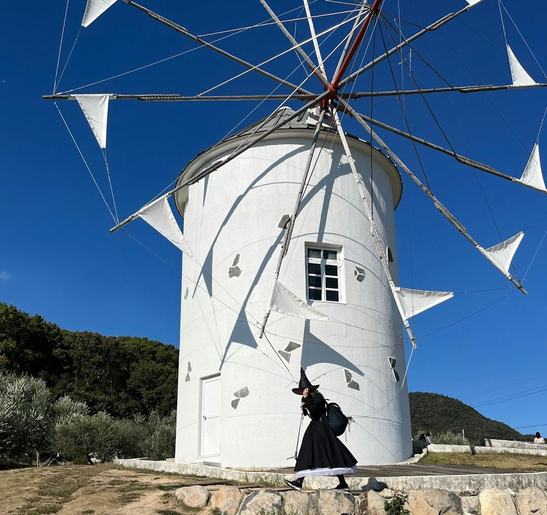 woman in a witch costume in front a windmill